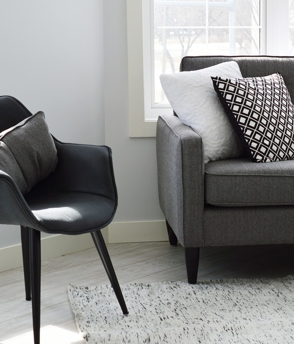 Poltrona e sofá cinza com almofadas decorativas lisas e estampadas